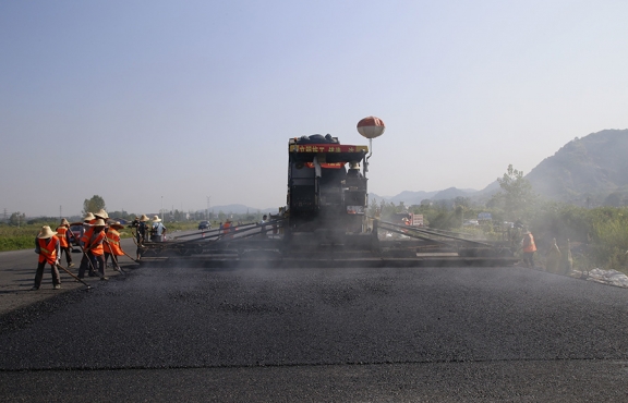 2019年8月，宜春經(jīng)開區(qū)S311路面攤鋪現(xiàn)場，工友們輔助路面兩側(cè)的分料、補窩等作業(yè)